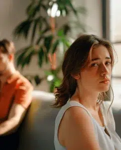 en la imagen aparece una mujer decepcionada y con su pareja de fondo. La mujer esta decepcionada porque cuando se estresa le trata mal