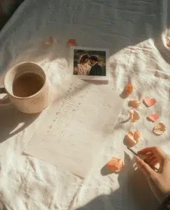una mano de una chica escribiendo una carta, con un café al lado y una foto de su pareja y pétalos que nos enumera las 10 cosas más importantes en una relación