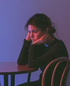 aparece una mujer sentada con los brazos en la mesa porque sufre frustración emocional