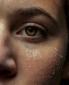 Primer plano de un rostro con el ojo abierto y la piel cubierta de sudor, reflejando tensión y malestar físico, una imagen que representa los síntomas de un ataque de celos, como la ansiedad intensa, la activación corporal, la inquietud y la pérdida de control emocional.