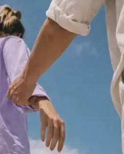 Una persona tira del brazo de otra que parece alejarse bajo un cielo despejado, una escena cargada de tensión emocional que refleja la confusión que surge al preguntarse **por qué mi ex actúa como si no le importara**, mientras uno intenta aferrarse y el otro parece seguir adelante.