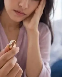 Mujer pensativa sosteniendo un anillo, una imagen que refleja si existe amor cuando hay infidelidad.