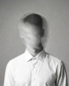 Persona con el rostro difuminado sobre fondo gris, representación visual de la alexitimia y la dificultad para identificar o expresar emociones.